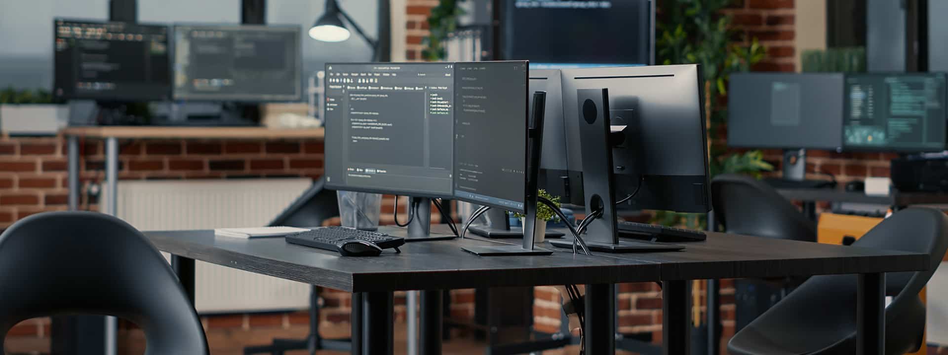 Multiple desk mounted black monitors in work office