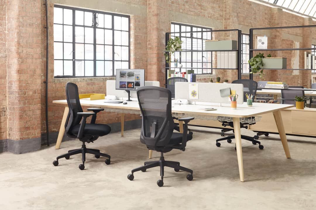 Wooden office table with black chairs and computers in rustic brick building