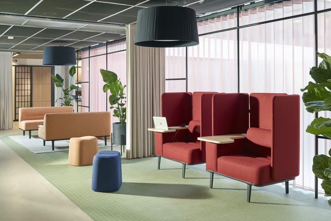Modern colourful office lounge area with fancy red chairs in foreground and pale yellow sofas in background