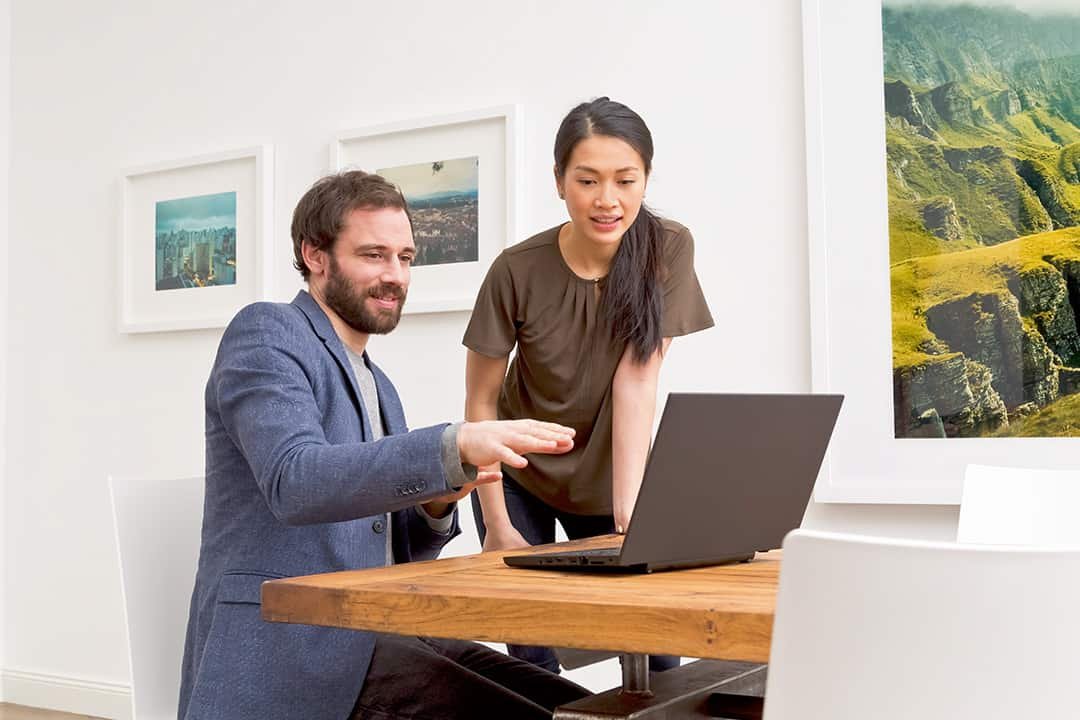 Man and woman having a conversation and using a laptop