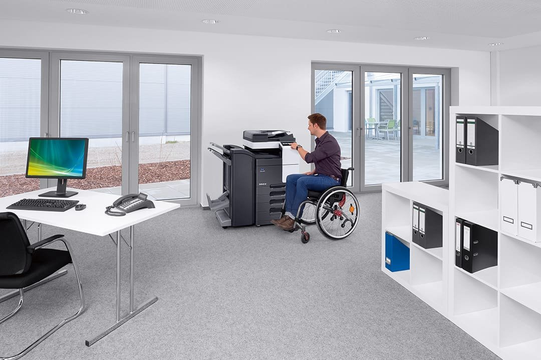 Man in a wheelchair using the office printer