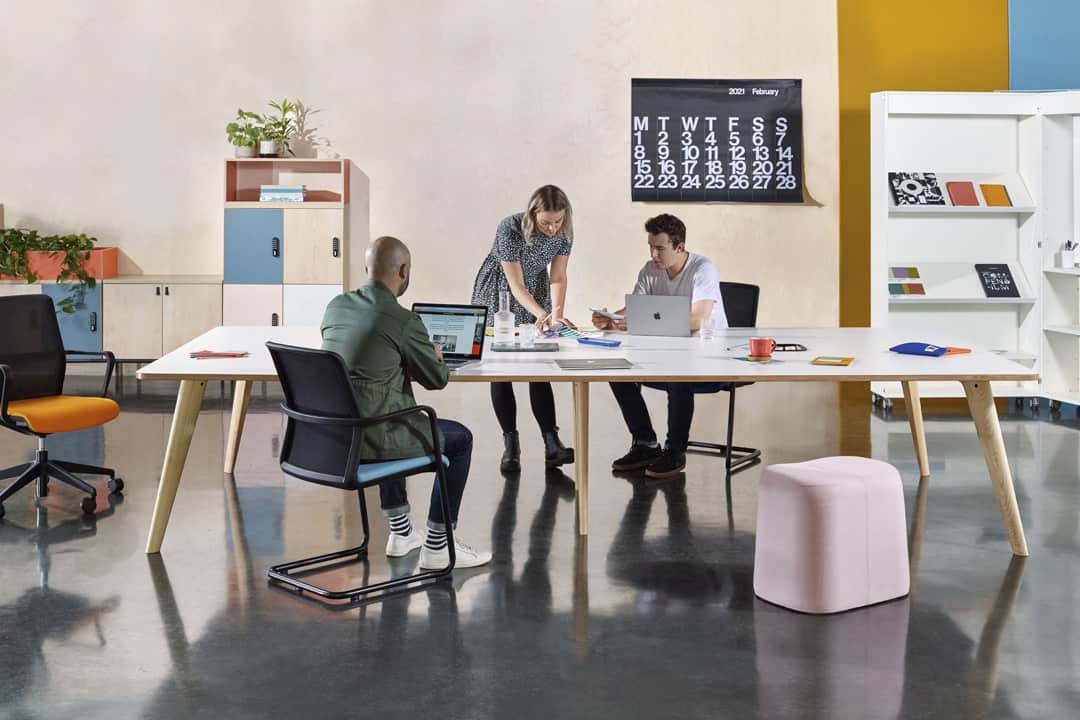 Two men and a woman having conversation at big office table