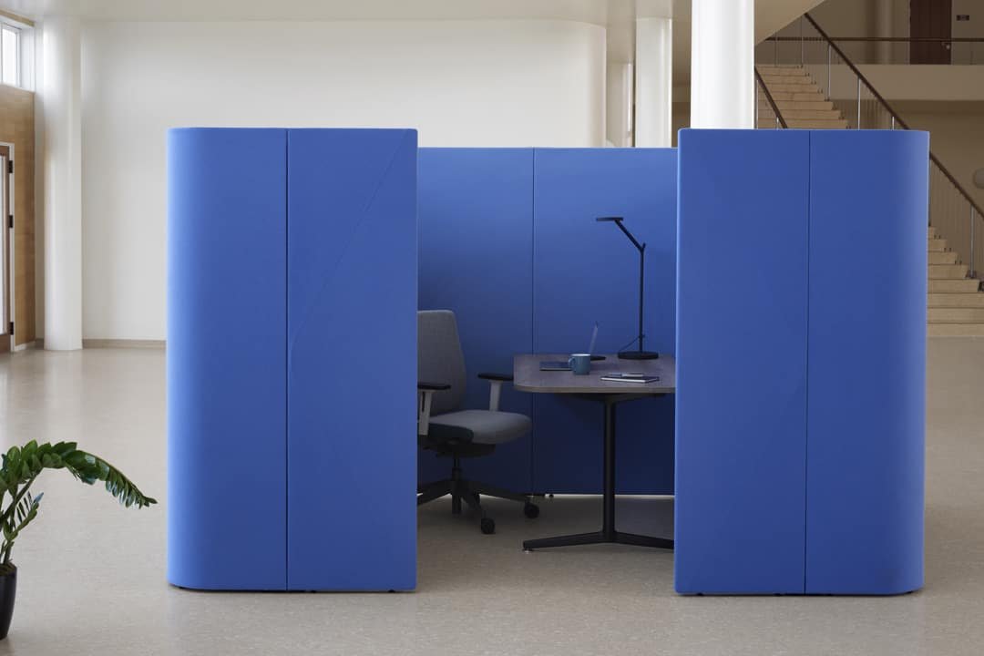 Blue walls in office environment surrounding the small desk and work chair.