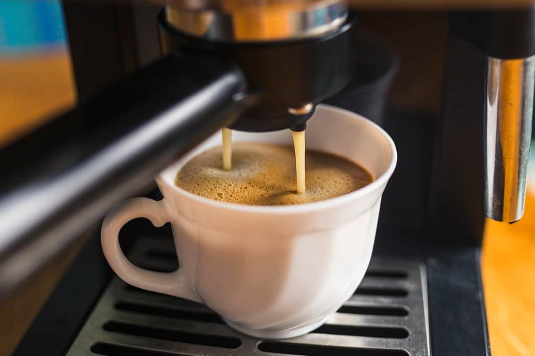 Coffee machine pouring coffee into white mug