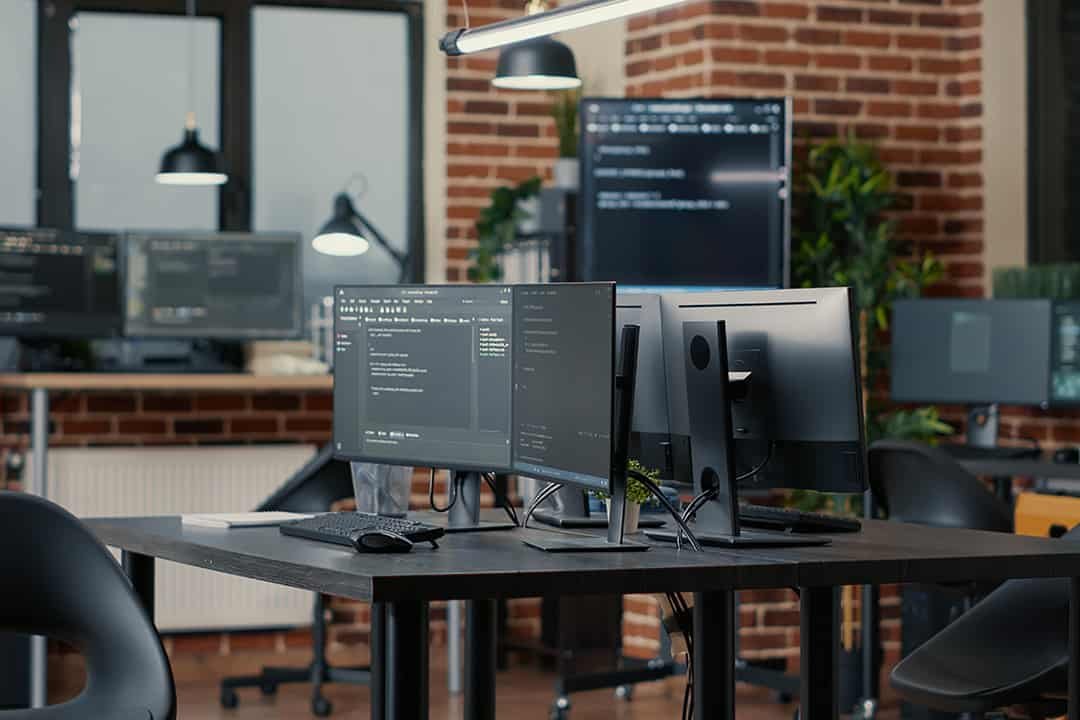 Multiple desk mounted black monitors in work office