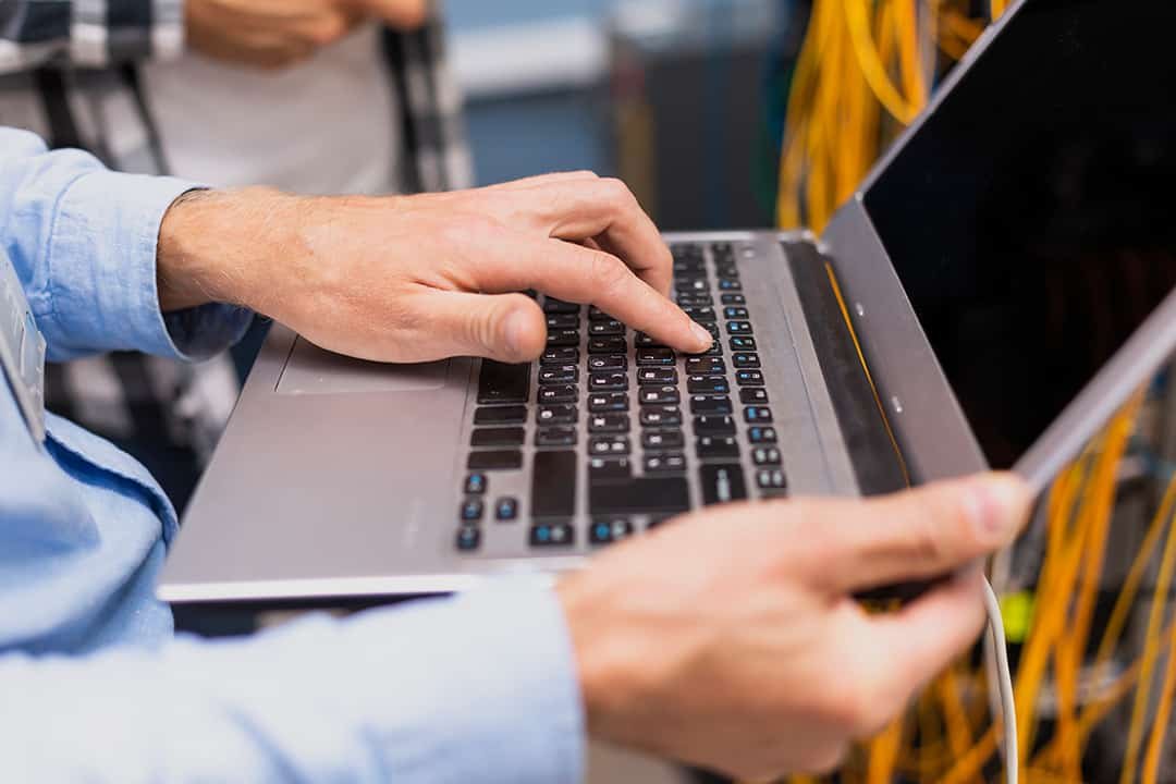 Close up of man holding laptop and pressing key on keyboard