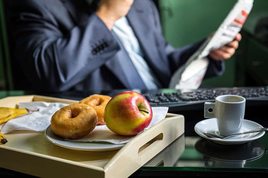 A tray with a plate of two donuts and an apple