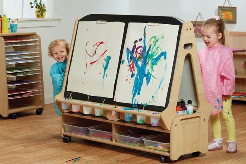Children smiling whilst painting on canvas